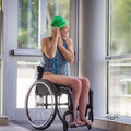 Image of a woman in a wheelchair putting her swim hat on