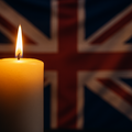 Lit candle with blurred Union Flag—symbolising mourning, unity, and quiet dignity without politicisation.