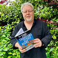 Author Dale Bradford, holding his novel, The Time-Travelling Estate Agent