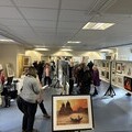 The downstairs hall of the Pop-Up Art Weekend with art enthusiasts appreciating the art on display.