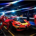 A Ferrari GT race car undergoing a precise nighttime pit stop, capturing the high-performance environment of Ferrari Competizioni GT.