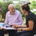 Older man and younger woman looking at a photo album. Photo from the Centre for Ageing Better