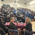 Three women sit in front of a group of 150 students at a school in South London