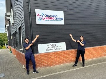 Christina and Shaz, two of the clinical team from the Chilterns Neuro  Centre, showing off the branding on the side of the Centre.