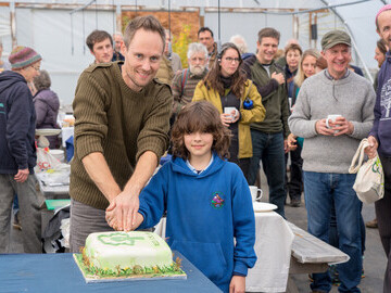 Volunteer and pupil cutting  the cake