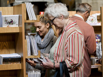 People Browsing At Cards For Good Causes Charity Shop