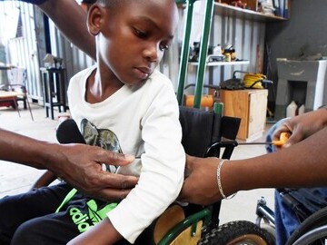 Photo of child being measured for postural support devices in Tanzania