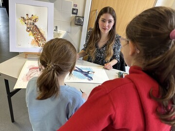 One of the artists giving a live demonstration of her skills to two young visitors to the exhibition.