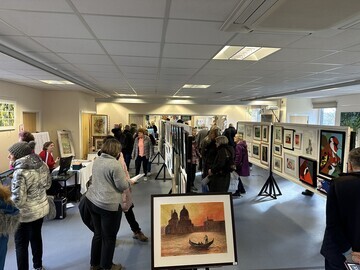 The downstairs hall of the Pop-Up Art Weekend with art enthusiasts appreciating the art on display.