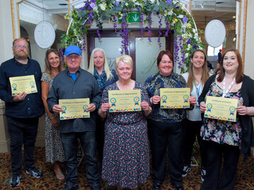 volunteers with the Coastline Homeless Service display their recognition certificates