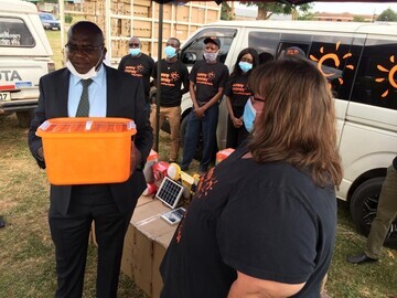 Karla Kanyanga, Operations Director, SolarAid in Zambia handing over solar lights to the Ministry of Health, Dr. Chitalu Chilufya.
