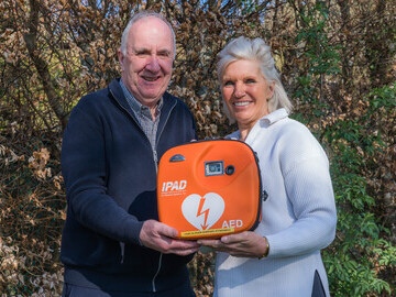 James Fraser, Chair of the Friends is pictured handing a defibrillator to Lucy Fraser who raised over £1,000