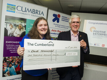 Chloe Pennington receives her £1,000 prize from David Beeby, Chair of Cumbria Community Foundation