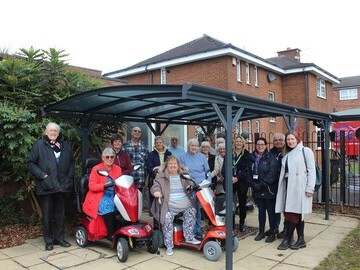 Users of the Bishop King Centre pose with staff from LHP under the new scooter shelter