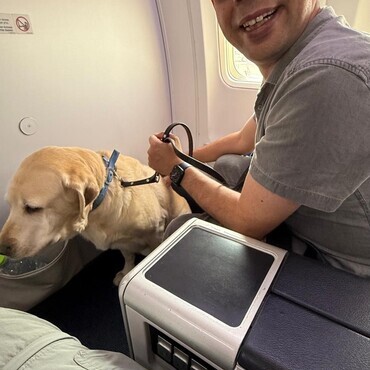 Guide dog user Elad Davidovich travelling with his guide dog Mirvis on board a flight supported by Animal Airways
